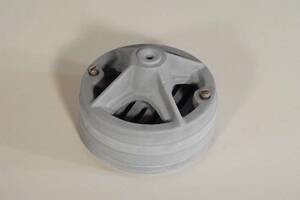 Gray circular plastic component with three radial spokes and a central hole, two screws visible on a white surface