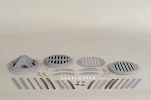 Assortment of metal vent covers and drain grates arranged on a white surface.