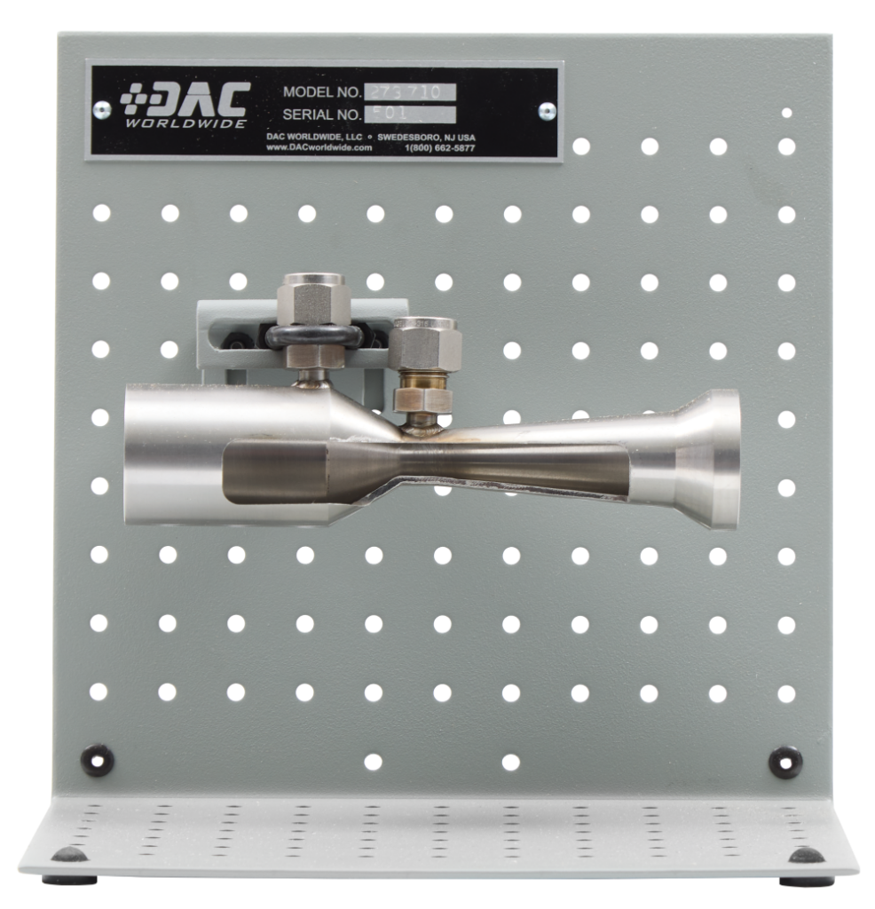 DAC Worldwide training panel featuring a stainless steel nozzle/valve assembly mounted on a gray perforated plate.