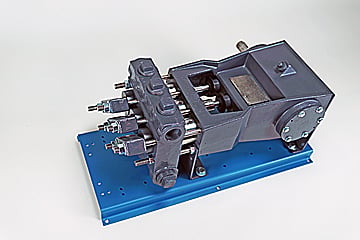 Industrial hydraulic valve manifold with ports and an electric actuator mounted on a blue baseplate