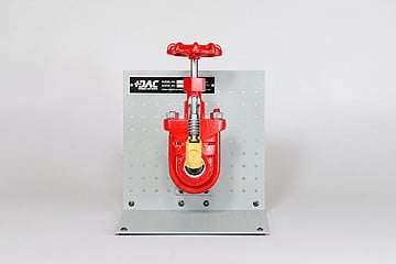 Red gate valve mounted on a perforated metal panel with a large wheel handle on a gray test stand