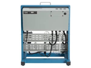 Back view of a blue industrial equipment rack with a gray enclosure and multiple black cables hanging beneath, showing wiring and perforated shelves in a lab or data center.