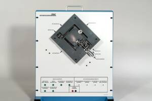 Electrical control panel with a tilted black actuator assembly mounted on a white surface; labeled switches, actuators, and a gate solenoid; blue frame and handle visible.