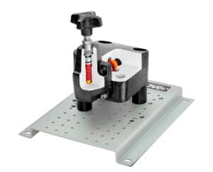 Compact bench vise mounted on a perforated metal base plate for securing workpieces.