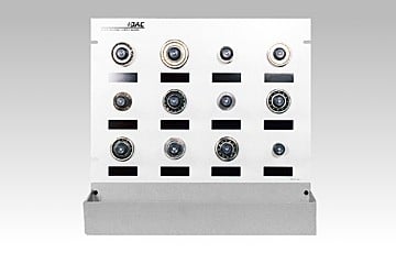 Metal control panel with twelve circular gauges arranged in four rows, mounted on a gray base.