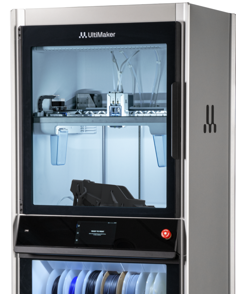 Front view of an Ultimaker 3D printer interior with the printing bed and multiple filament spools visible inside the cabinet.
