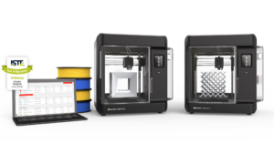 Two MakerBot Sketch 3D printers on a white surface, with a laptop showing a project dashboard and nearby filament spools in yellow, blue, and black bands.