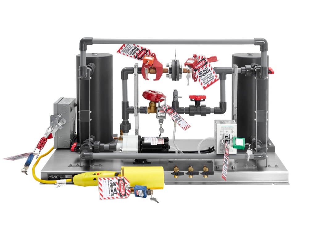 Industrial test rig with pipes, valves and safety warning tags reading 'DANGER DO NOT OPERATE' spread across the apparatus.